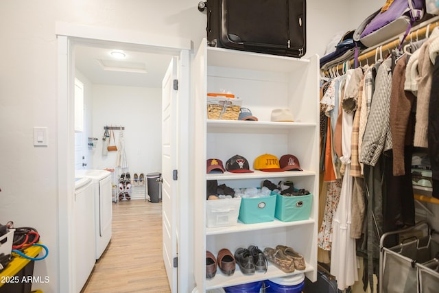 spacious closet with attic access, separate washer and dryer, and light wood-style flooring