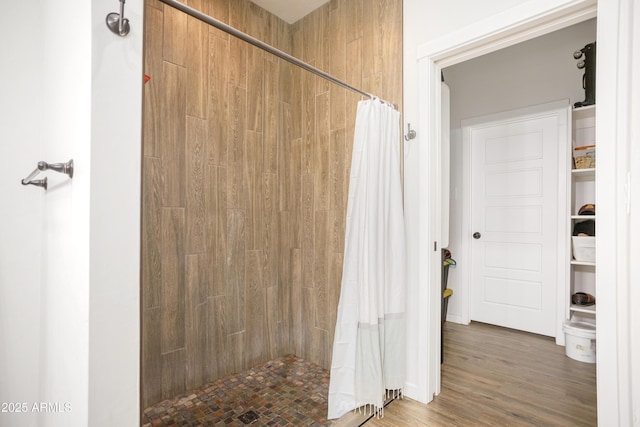full bath featuring wood finished floors and a tile shower