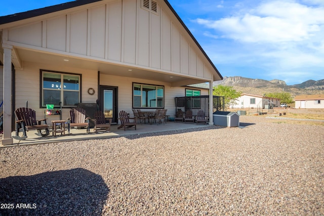 rear view of house with a patio, an outbuilding, a mountain view, a shed, and board and batten siding