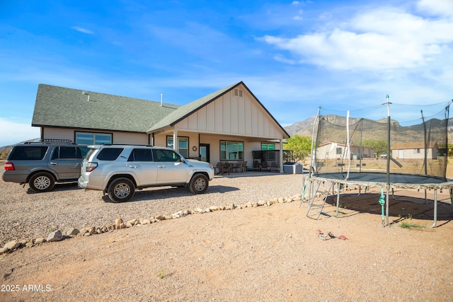 view of front of property featuring a mountain view, a trampoline, board and batten siding, and roof with shingles
