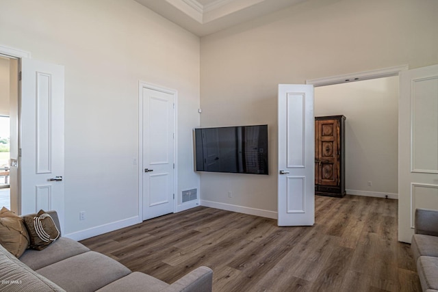 living room featuring a high ceiling, wood finished floors, visible vents, and baseboards