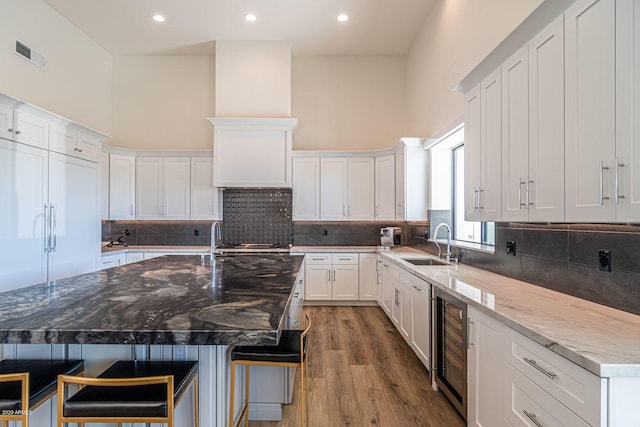 kitchen with wine cooler, a sink, visible vents, and white cabinetry