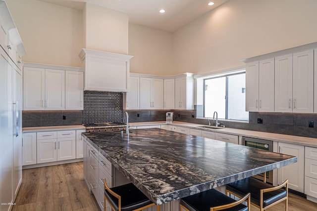 kitchen with a breakfast bar area, beverage cooler, a high ceiling, paneled built in fridge, and a sink