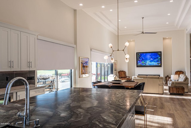 kitchen featuring open floor plan, crown molding, a towering ceiling, and wood finished floors