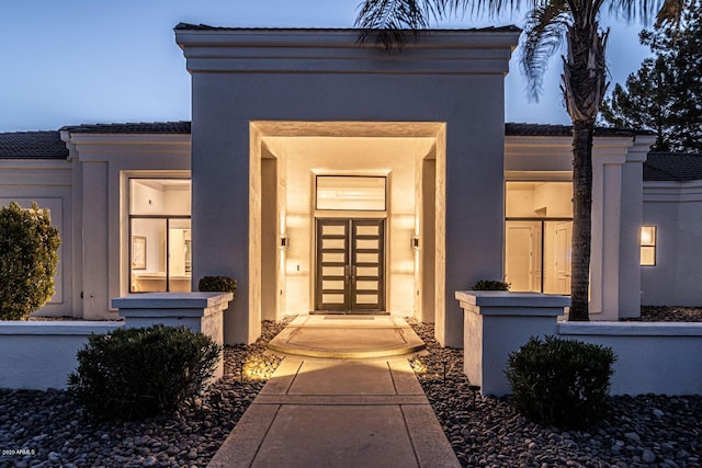 property entrance featuring a tile roof and stucco siding