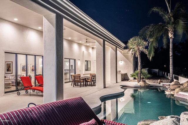 pool at twilight featuring an outdoor pool, a ceiling fan, and a patio