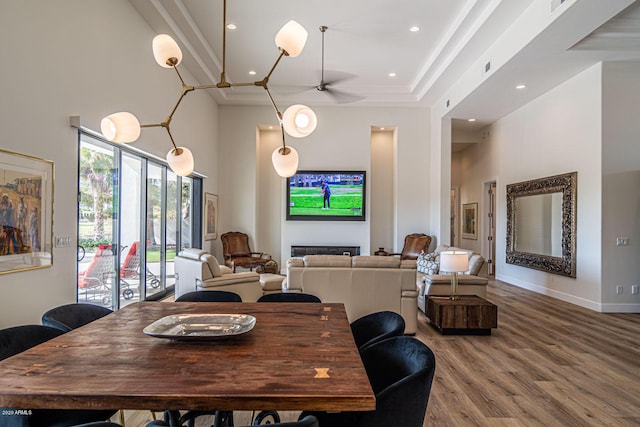 dining space featuring a fireplace, recessed lighting, a high ceiling, wood finished floors, and baseboards