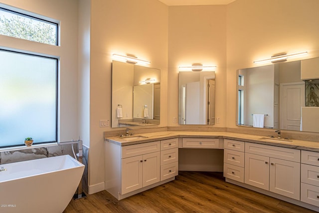 full bath featuring a healthy amount of sunlight, a high ceiling, and wood finished floors