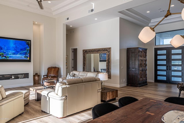 living room with a tray ceiling, visible vents, a high ceiling, and wood finished floors