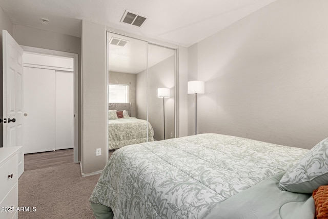 carpeted bedroom with visible vents and a closet