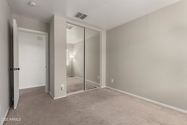 unfurnished bedroom with carpet floors, baseboards, visible vents, and a closet