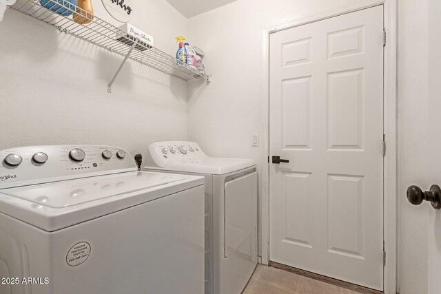 washroom featuring laundry area, washer and clothes dryer, and light tile patterned flooring