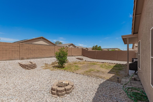 view of yard with a fenced backyard and a fire pit