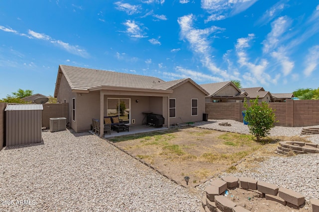 back of property with an outdoor structure, stucco siding, a shed, a fenced backyard, and a patio
