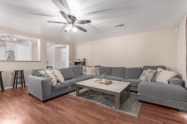 living room with a ceiling fan, wood finished floors, and visible vents