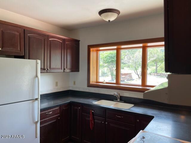 kitchen featuring white fridge, dark brown cabinetry, and sink