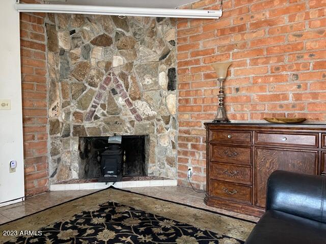 unfurnished living room with a wood stove and brick wall