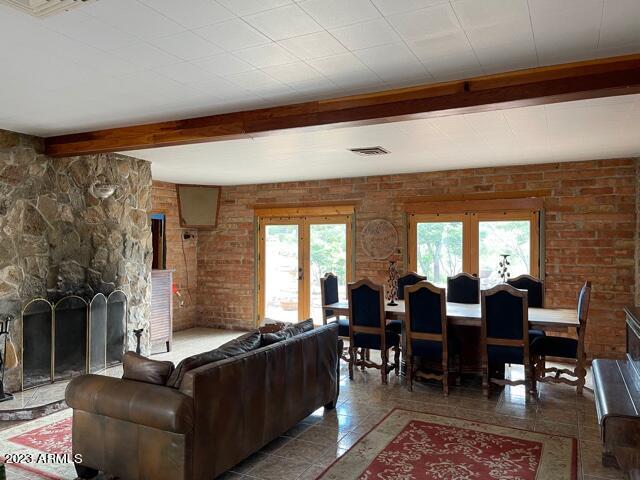 living room featuring beam ceiling, dark tile flooring, french doors, and a fireplace