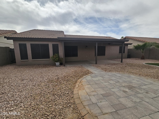 rear view of house with a tiled roof, a patio area, fence, and stucco siding