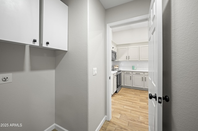 laundry area with a textured wall, wood tiled floor, hookup for an electric dryer, laundry area, and baseboards