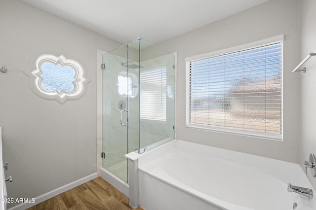 bathroom with wood finished floors, a shower stall, baseboards, and a bath