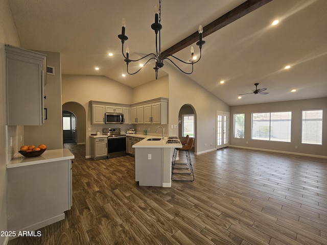 kitchen with arched walkways, open floor plan, a peninsula, stainless steel appliances, and a sink