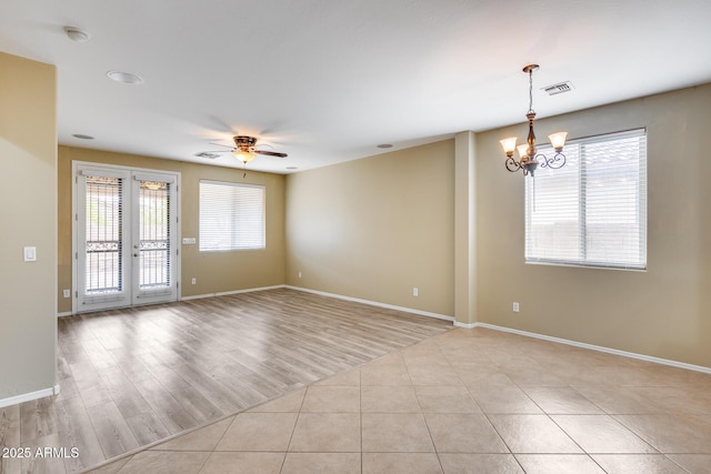 spare room featuring french doors, visible vents, light tile patterned flooring, baseboards, and ceiling fan with notable chandelier