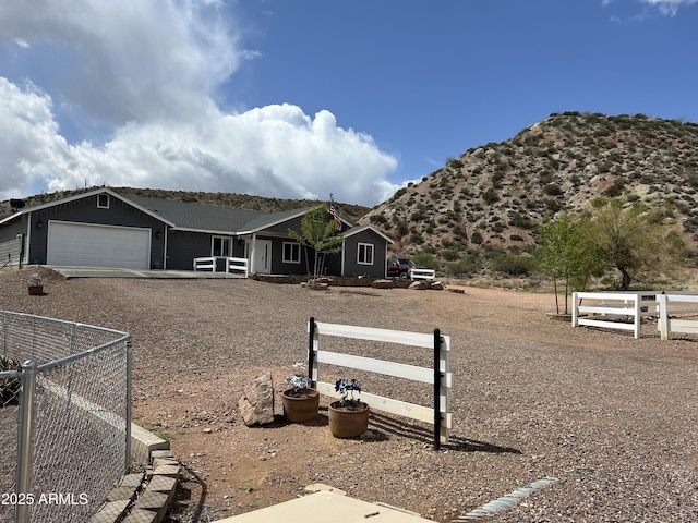 ranch-style home with an attached garage, driveway, a mountain view, and fence