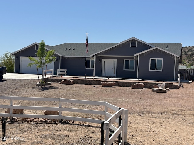 ranch-style home with a garage, a fenced front yard, and dirt driveway
