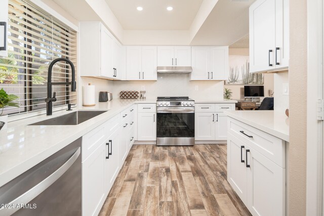 kitchen with light hardwood / wood-style floors, white cabinets, stainless steel appliances, and sink