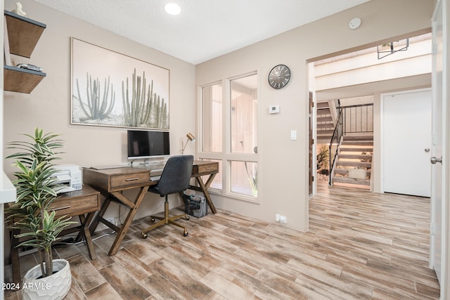 home office with a textured ceiling and light hardwood / wood-style floors