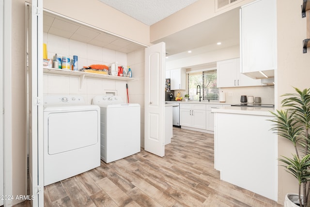 washroom featuring sink, washer and clothes dryer, a textured ceiling, and light wood-type flooring