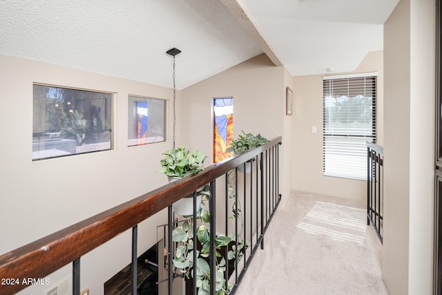 corridor featuring lofted ceiling, a textured ceiling, and light colored carpet