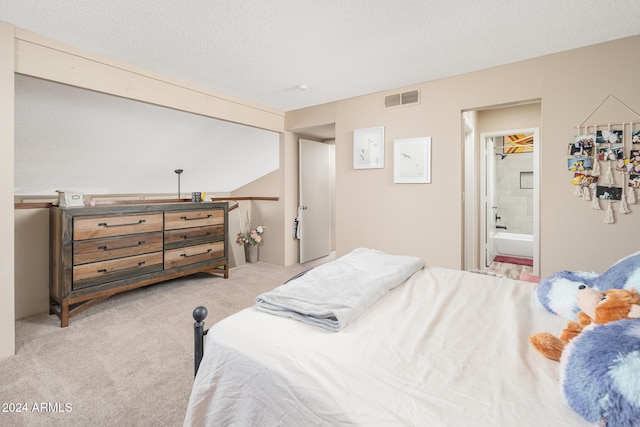 bedroom with connected bathroom, a textured ceiling, and light colored carpet