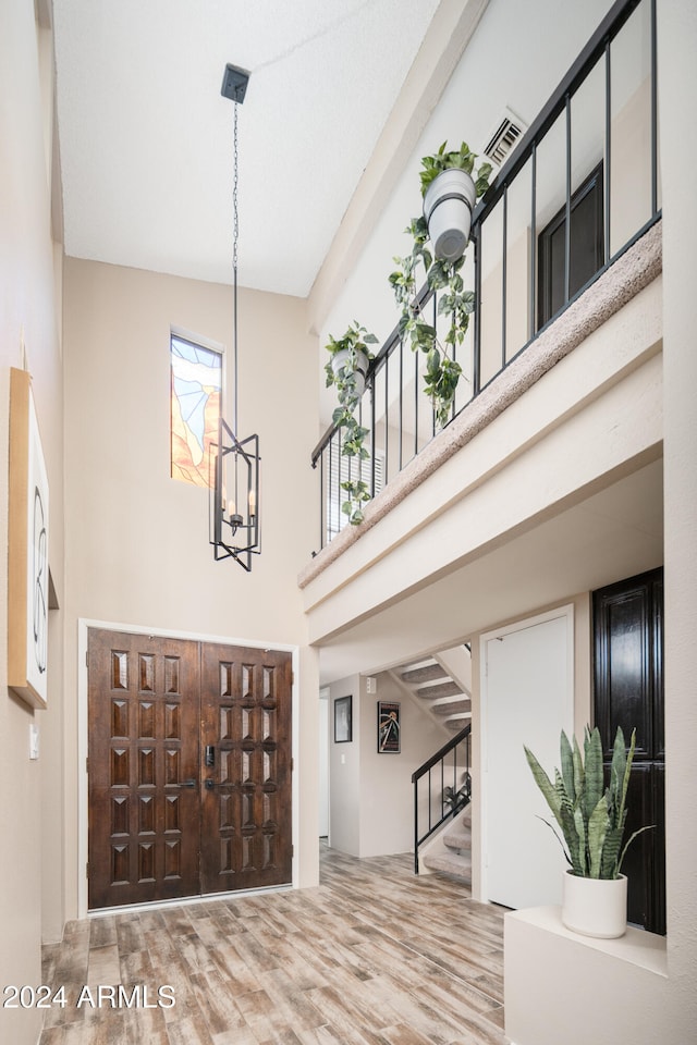 foyer with high vaulted ceiling, a chandelier, and hardwood / wood-style floors