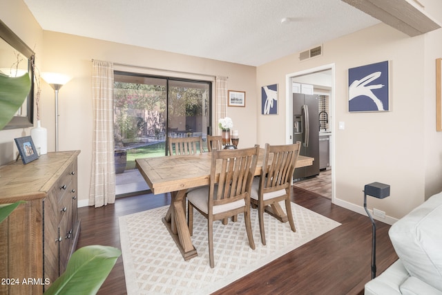 dining room featuring dark wood-type flooring and a textured ceiling