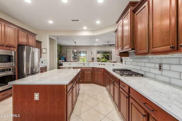 kitchen with appliances with stainless steel finishes, sink, a kitchen island, ceiling fan, and pendant lighting