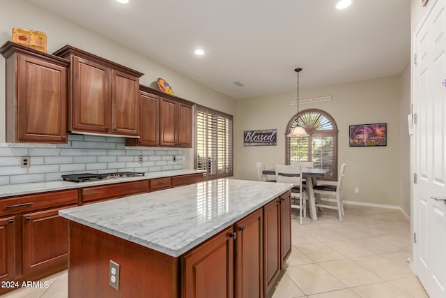 kitchen featuring light tile patterned floors, backsplash, stainless steel gas stovetop, decorative light fixtures, and a center island