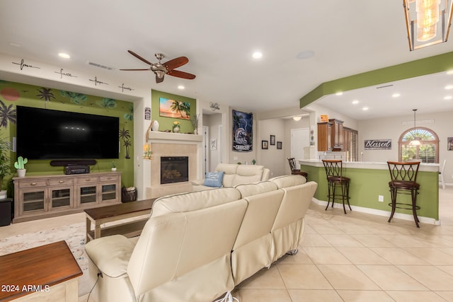 living room featuring a fireplace, light tile patterned floors, and ceiling fan