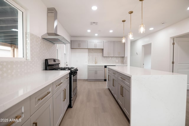 kitchen with wall chimney exhaust hood, gas stove, a center island, light wood-type flooring, and gray cabinets