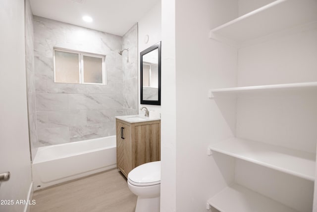 full bathroom with hardwood / wood-style floors, vanity, tiled shower / bath, and toilet