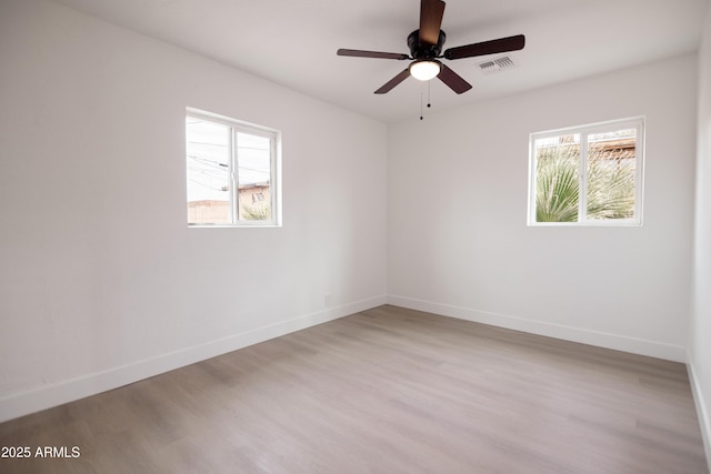 empty room with ceiling fan, a healthy amount of sunlight, and light wood-type flooring