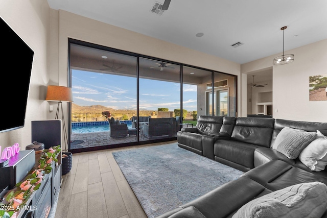 living room featuring ceiling fan, light hardwood / wood-style flooring, and a mountain view