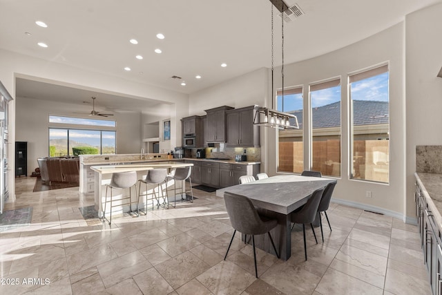 dining space with ceiling fan with notable chandelier and a wealth of natural light