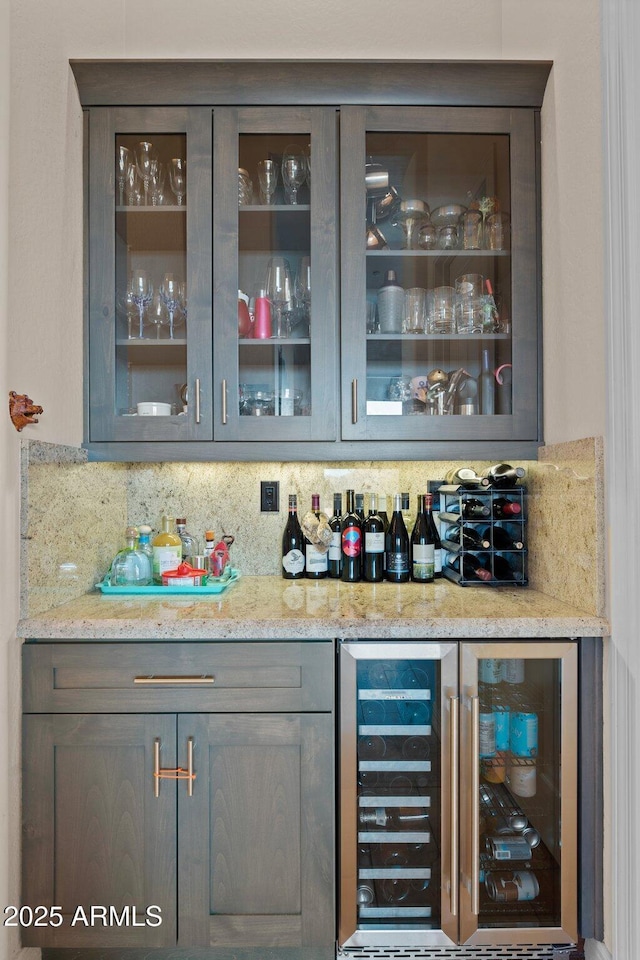 bar featuring tasteful backsplash, beverage cooler, and light stone counters