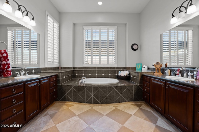 bathroom featuring a relaxing tiled tub and vanity