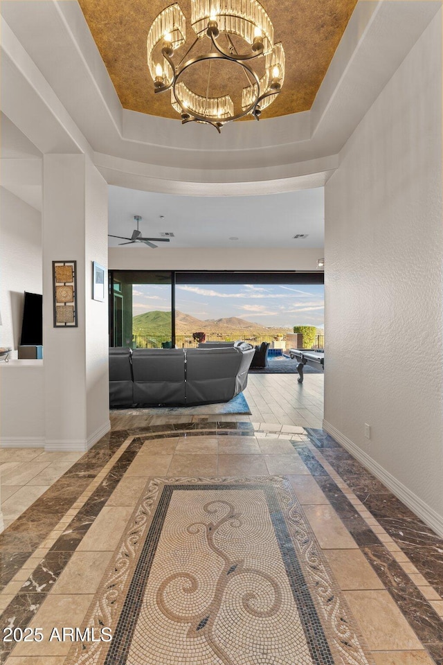 corridor featuring a chandelier and a raised ceiling