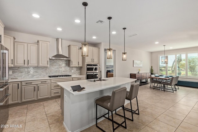 kitchen featuring black cooktop, a sink, visible vents, wall chimney range hood, and decorative backsplash