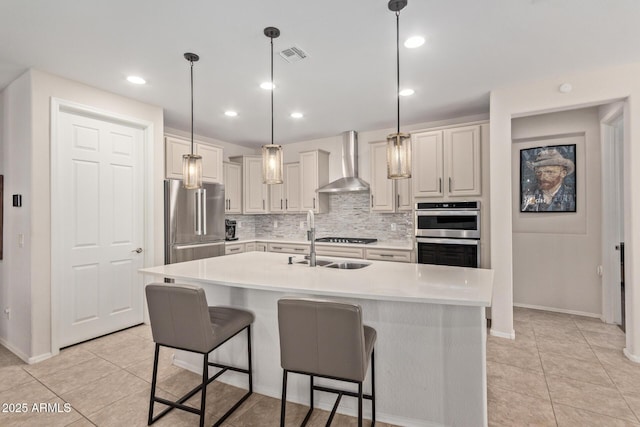 kitchen featuring wall chimney exhaust hood, appliances with stainless steel finishes, light countertops, and visible vents