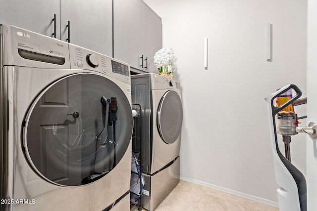 clothes washing area with cabinet space, baseboards, washer and clothes dryer, and light tile patterned flooring